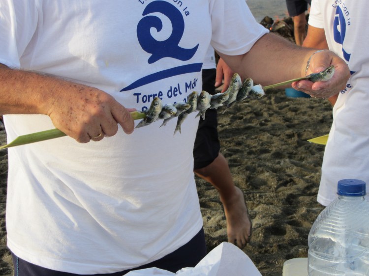 threading the sardines onto the bamboo skewers