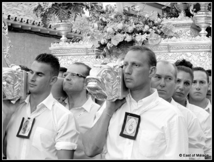 Solemn faces as they carry the statue through the streets